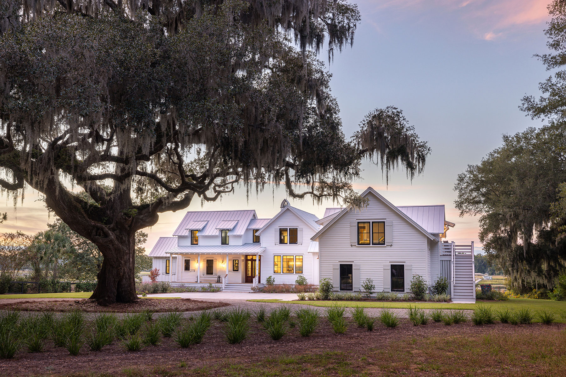 Custom home at sunset with large Grand Oak in the front of the property