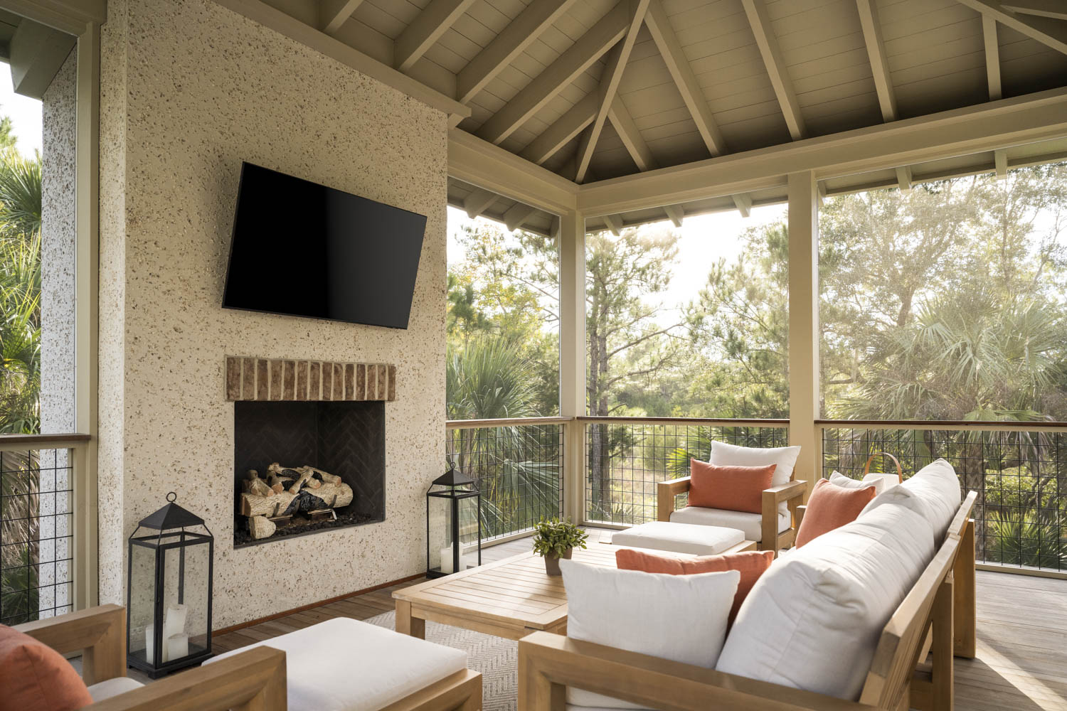 Outdoor TV Patio Space Outdoor patio with television mounted to oyster shell tabby wall. White and wood patio furniture with peach-colored pillows.