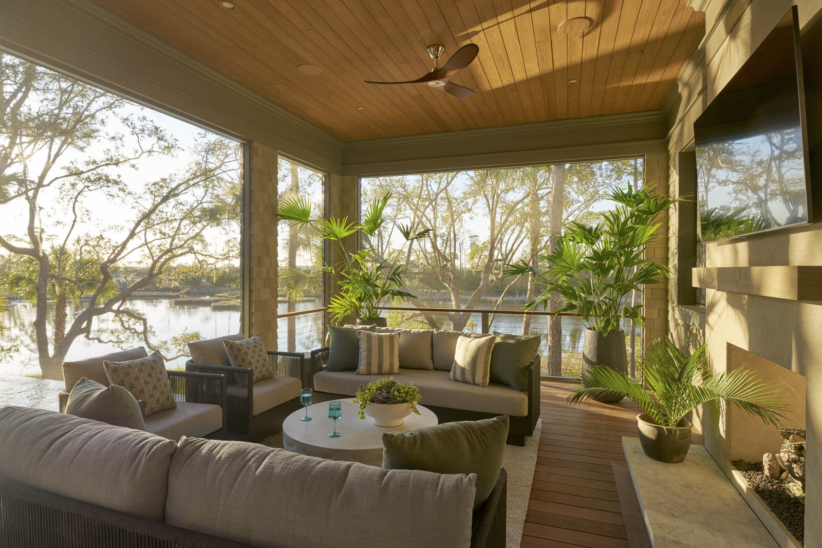 Sage-horizontal-back-porch-angle Round dining room table overlooking the marsh. Exposed ceiling beams with shiplap ceiling and textured wallpaper.